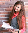 Smiling young business woman with document over brickwall