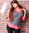Smiling young business woman with document over brickwall