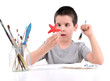 Crossed-eyed boy painting star fish over white.