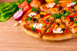 pizza and vegetables on wooden background