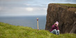 Woman sitting in grass on cliff of the island of Mykines Woman sitting in grass on cliff of the island of Mykines