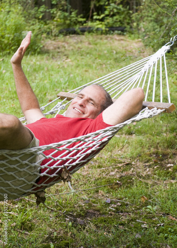 Photo: smiling middle age man relaxing in hammock smiling middle age man relaxing in hammock