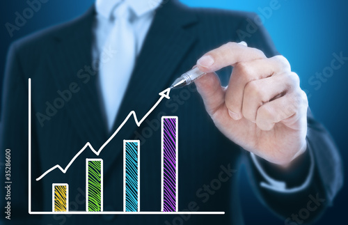 Photo: businessman writing rising graph ,blue background businessman writing rising graph ,blue background