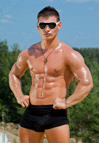 Photo: Muscle sexy wet naked young man posing on the beach Muscle sexy wet naked young man posing on the beach