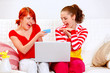 Two smiling girlfriends making purchase using credit card