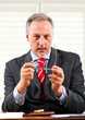 Thoughtful elder businessman holding a pair of glasses
