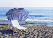 Chaise lounge with umbrella standing alone near of the blue sea. Chaise lounge with umbrella standing alone near of the blue sea.