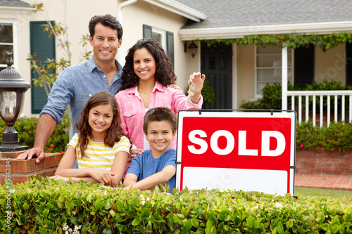Photo: Hispanic family outside home with sold sign Hispanic family outside home with sold sign
