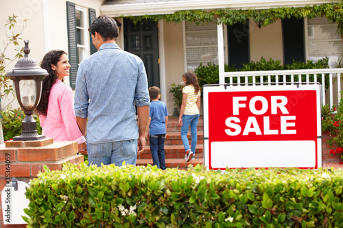 Photo: Hispanic family outside home with for sale sign Hispanic family outside home with for sale sign