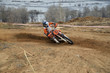 Motorbike racer turns sharply to the on a sandy track