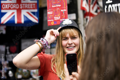 Photo: A teenage girl trying on a policeman's helmet in a souvenir shop A teenage girl trying on a policeman's helmet in a souvenir shop