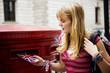 A teenage girl putting postcards into a red letterbox