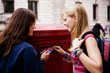 Two teenage girls putting postcards into a red letterbox