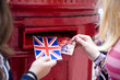 Foto: Two teenage girls putting postcards into a red letterbox Two teenage girls putting postcards into a red letterbox