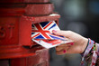 Foto: A teenage girl putting postcards into a red letterbox A teenage girl putting postcards into a red letterbox