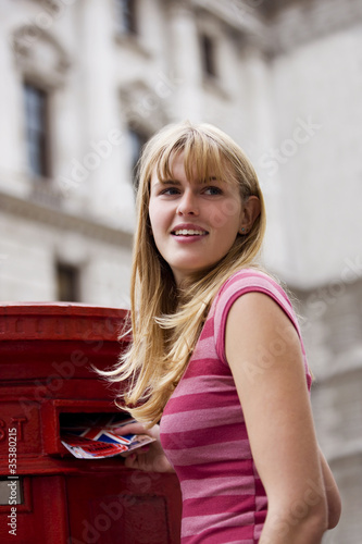 Foto: A teenage girl putting postcards into a red letterbox A teenage girl putting postcards into a red letterbox
