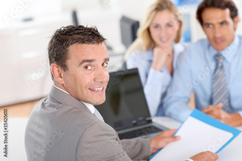 Photo: Couple with real-estate agent in office Couple with real-estate agent in office