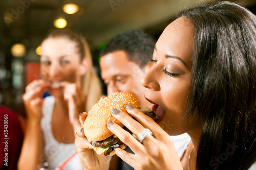 Photo: Friends eating fast food in a restaurant Friends eating fast food in a restaurant
