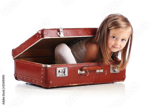 Photo: Happy small girl sitting in a suitcase. Travel concept. Isolated Happy small girl sitting in a suitcase. Travel concept. Isolated