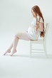 Beautiful young pregnant woman sitting on chair