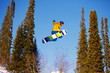 Snowboarder jumping through air with  blue sky in background