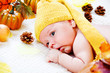 Infant  among autumnal leaves and pumpkins