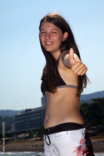 Foto: Junges Mädchen im Urlaub hält lachend Daumen hoch Junges Mädchen im Urlaub hält lachend Daumen hoch
