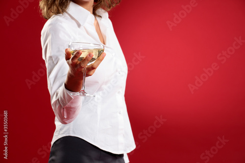 Photo: young woman with a glass of champagne on red background young woman with a glass of champagne on red background