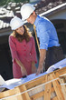 Foto: Man & Woman In Hard Hats on Construction Site Man & Woman In Hard Hats on Construction Site