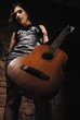 Girl with a guitar near a brick wall