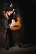 Girl with a guitar near a brick wall