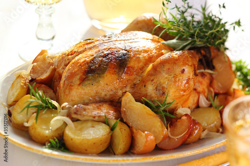 Photo: Whole roasted chicken with potatoes and apples on white plate Whole roasted chicken with potatoes and apples on white plate