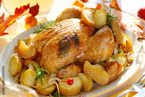 Photo: Whole roasted chicken with potatoes and apples on white plate Whole roasted chicken with potatoes and apples on white plate