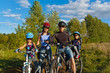 Family cycling outdoors. Happy parents with two kids on bikes