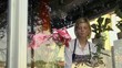 Blonde girl working in flowers shop with roses and gerbera