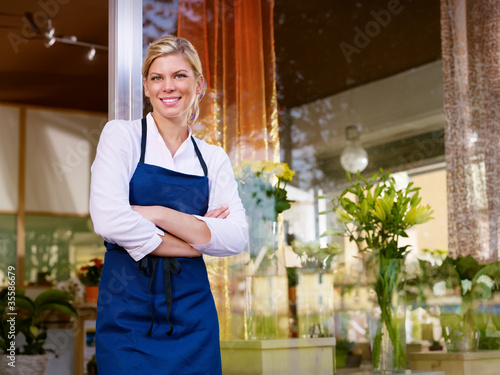 Photo: Young pretty woman working as florist in shop and smiling Young pretty woman working as florist in shop and smiling