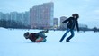 The adult boy spins the sled around in the winter