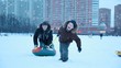 Young boy is pulling sled hardly with other boy