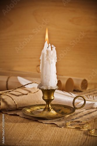 Foto: view on the burning candle with old notes sheet view on the burning candle with old notes sheet
