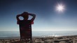 Woman sitting on deckchair and holding hand behind head