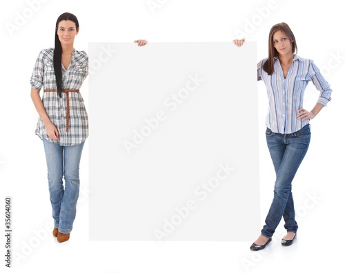 Photo: Attractive women holding blank sheet Attractive women holding blank sheet