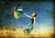 Redhead girl with umbrella at windy grass meadow.