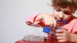 Little girl put white marbles in shopping cart model