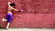 Flexible girl dances near red brick wall
