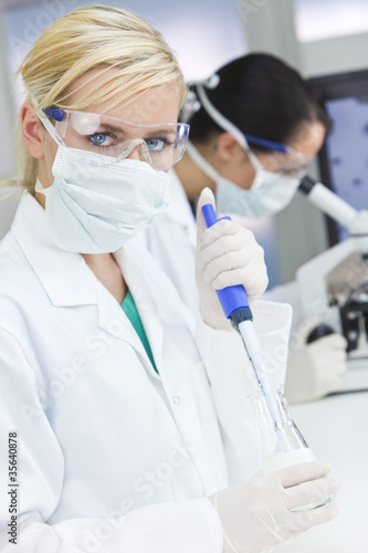 Photo: Female Scientist Doctors, Pipette & Microscope in a Laboratory Female Scientist Doctors, Pipette & Microscope in a Laboratory