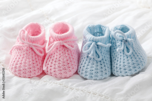 Photo: Blue and pink baby booties on white background Blue and pink baby booties on white background
