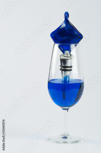 Photo: A glass filled with blue substance and an ornament A glass filled with blue substance and an ornament