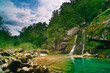 Small waterfall in mountain forest and turquoise lake Small waterfall in mountain forest and turquoise lake
