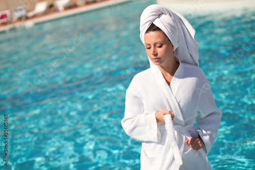 Photo: girl in a white coat at the outdoor swimming pool girl in a white coat at the outdoor swimming pool