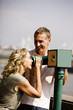A middle-aged couple using a telescope, laughing